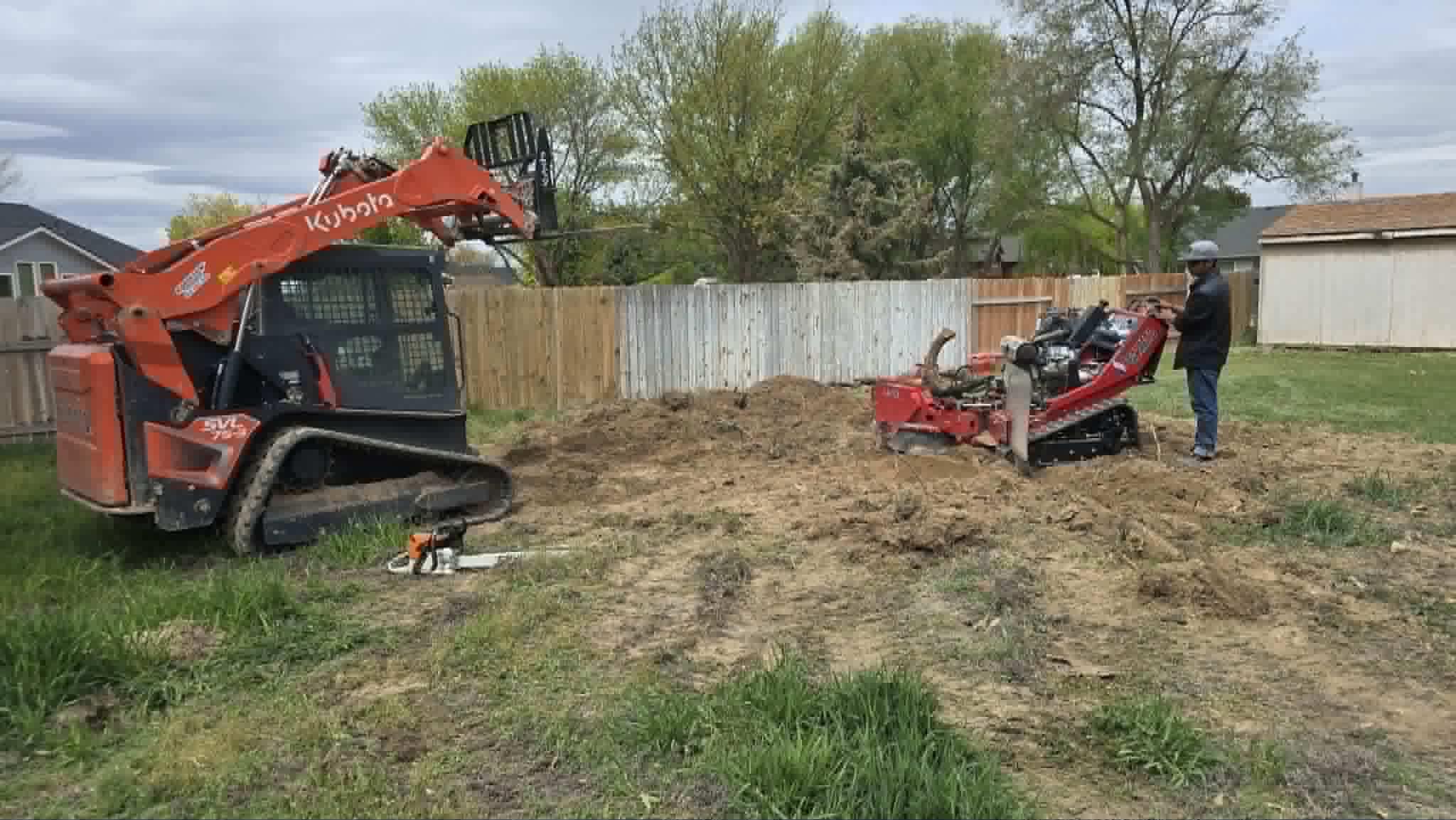 Cargador compacto y equipo de árboles en un trabajo residencial